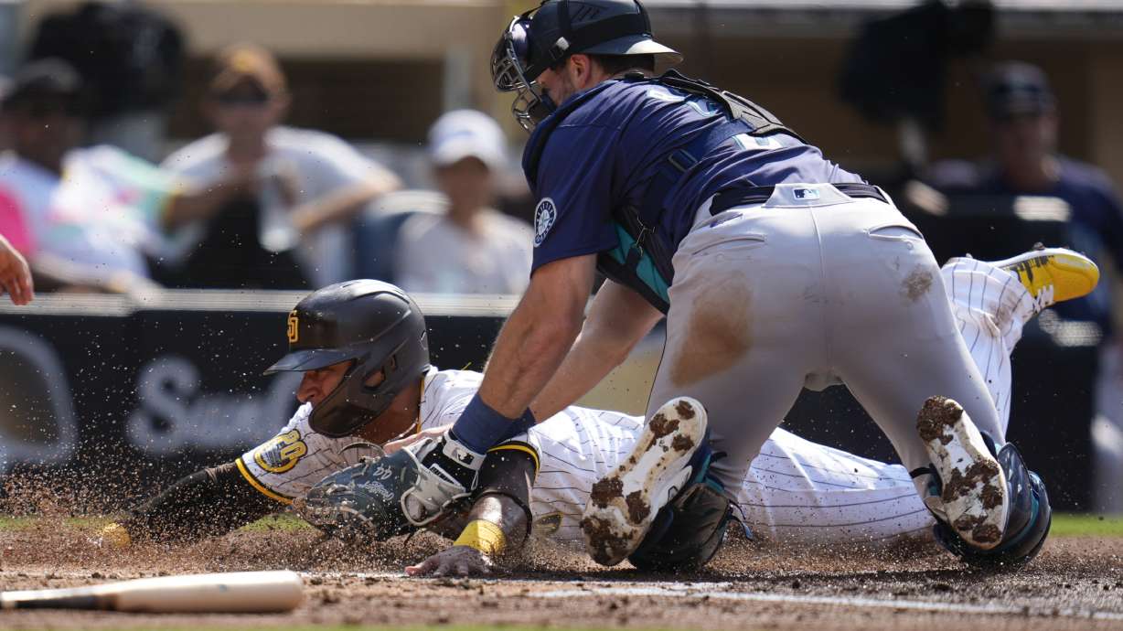San Diego Padres' Donovan Solano, left, is tagged out at home by Seattle Mariners catcher Cal Raleigh during the second inning of a baseball game Wednesday, July 10, 2024, in San Diego.