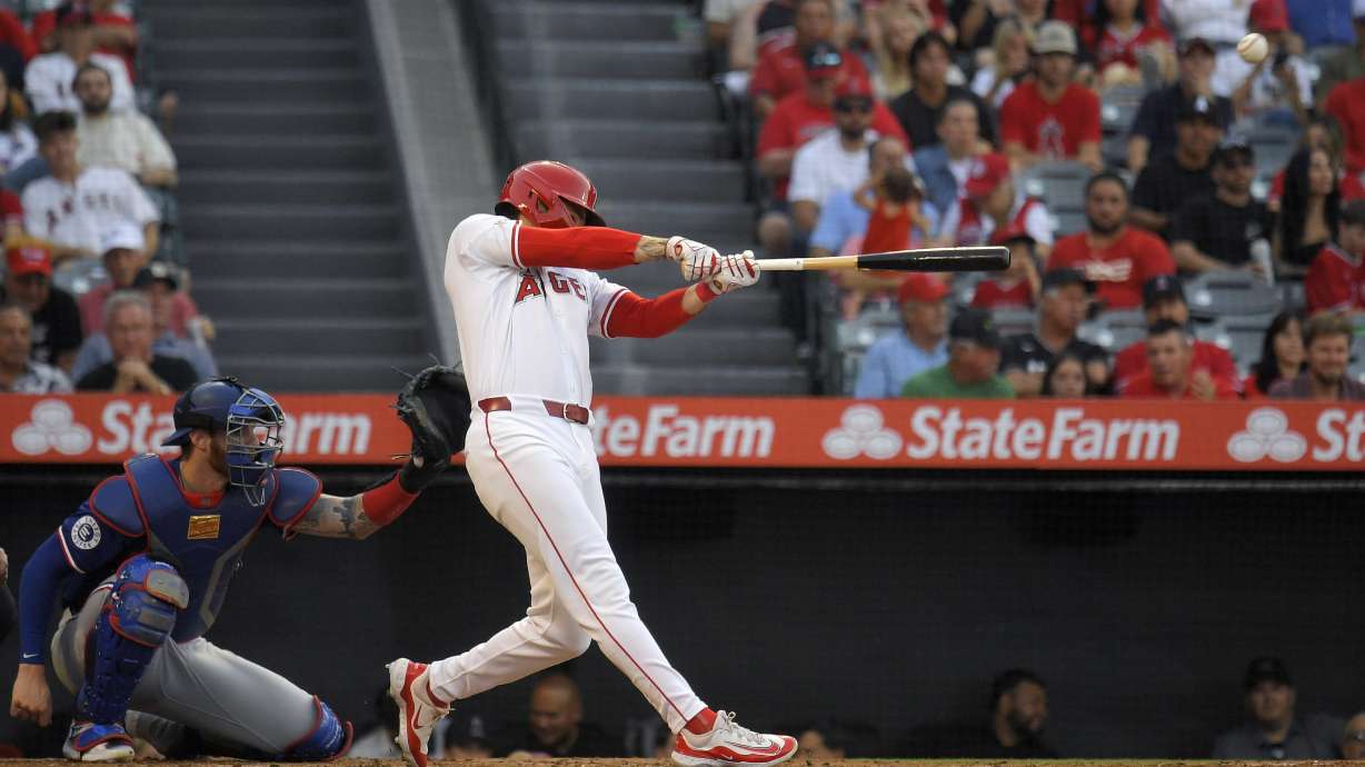 Los Angeles Angels' Mickey Moniak, right, hits a three-run home run as Texas Rangers catcher Jonah Heim watches during the second inning of a baseball game Wednesday, July 10, 2024, in Anaheim, Calif.
