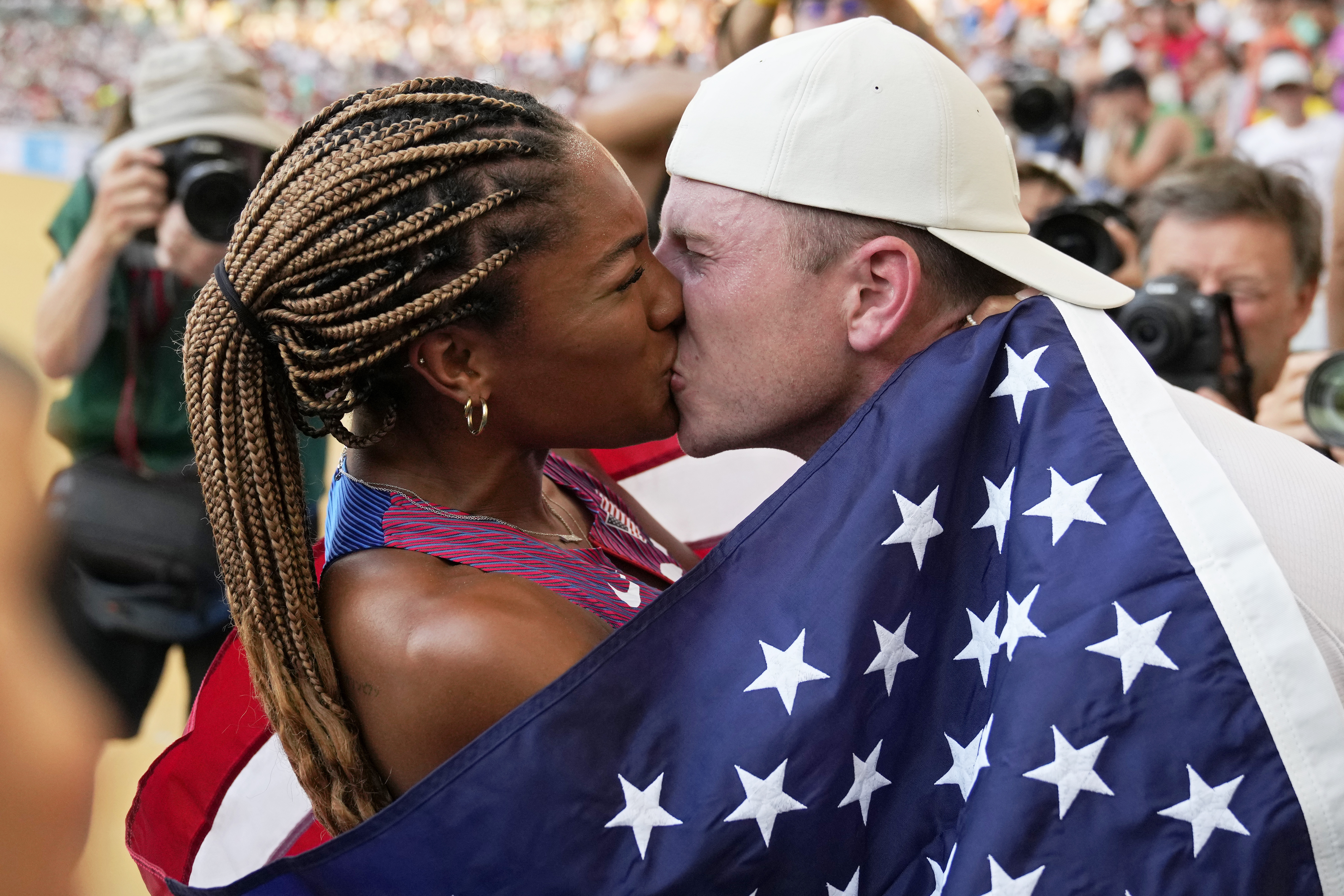 FILE - Tara Davis-Woodhall, of the United States, gets a kiss from her husband Hunter Woodhall after winning the silver medal in the women's long jump final during the World Athletics Championships in Budapest, Hungary, Sunday, Aug. 20, 2023. They are track and field's power couple. Long jumper Tara Davis-Woodhall and her husband, Hunter Woodhall, are on a quest to make this Olympic year better than any before it.