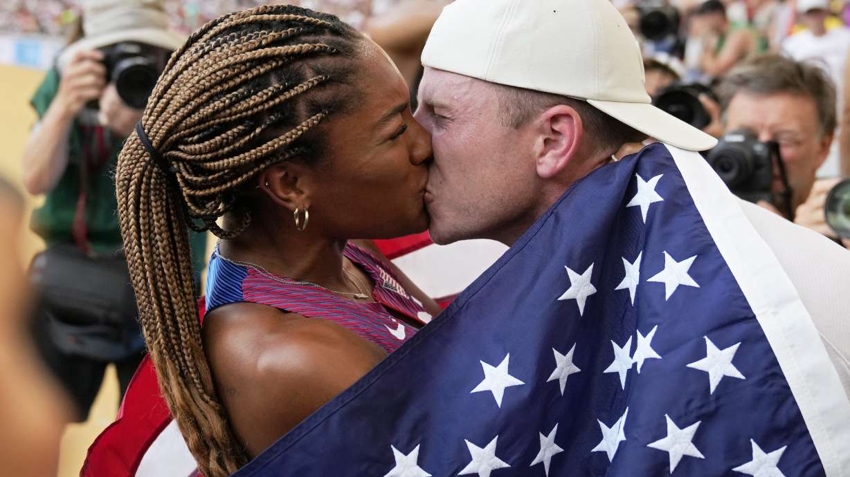 FILE - Tara Davis-Woodhall, of the United States, gets a kiss from her husband Hunter Woodhall after winning the silver medal in the women's long jump final during the World Athletics Championships in Budapest, Hungary, Sunday, Aug. 20, 2023. They are track and field's power couple. Long jumper Tara Davis-Woodhall and her husband, Hunter Woodhall, are on a quest to make this Olympic year better than any before it.