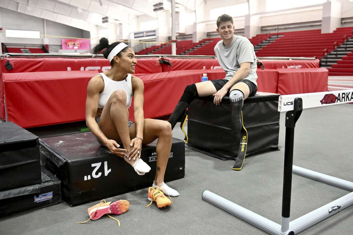 Olympic long jumper Tara Davis-Woodhall, left, talks with her husband, Paralympian sprinter Hunter Woodhall, after finishing their workout at the Randal Tyson Track Center, Thursday Jan. 18, 2024, in Fayetteville, Ark. Standing near the track one day, a runner caught Tara’s eye. He was wearing sweatpants, so she didn’t notice his prosthetics at first.