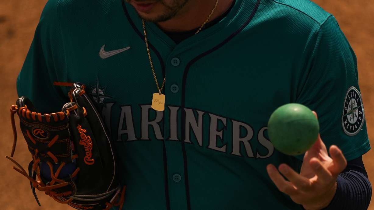 FILE - Seattle Mariners relief pitcher Tayler Saucedo uses a weighted ball to warm up in the bullpen before a spring training baseball game against the Kansas City Royals, March 6, 2024, in Surprise, Ariz. Velocity training is the rage in baseball from the youth levels up through the majors. Players go through specialized programs – often using series of progressively weighted baseballs – in the hopes of speeding up their bodies and arms, pushing them to the limits of what might be possible for their age and ability.