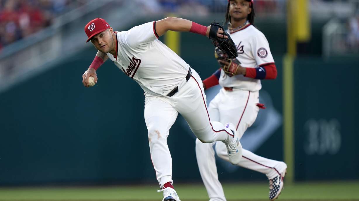 Washington Nationals third baseman Nick Senzel, left, throws an infield ground ball to first base ahead of shortstop CJ Abrams, right, during the fifth inning of a baseball game against the New York Mets at Nationals Park, Monday, July 1, 2024, in Washington.