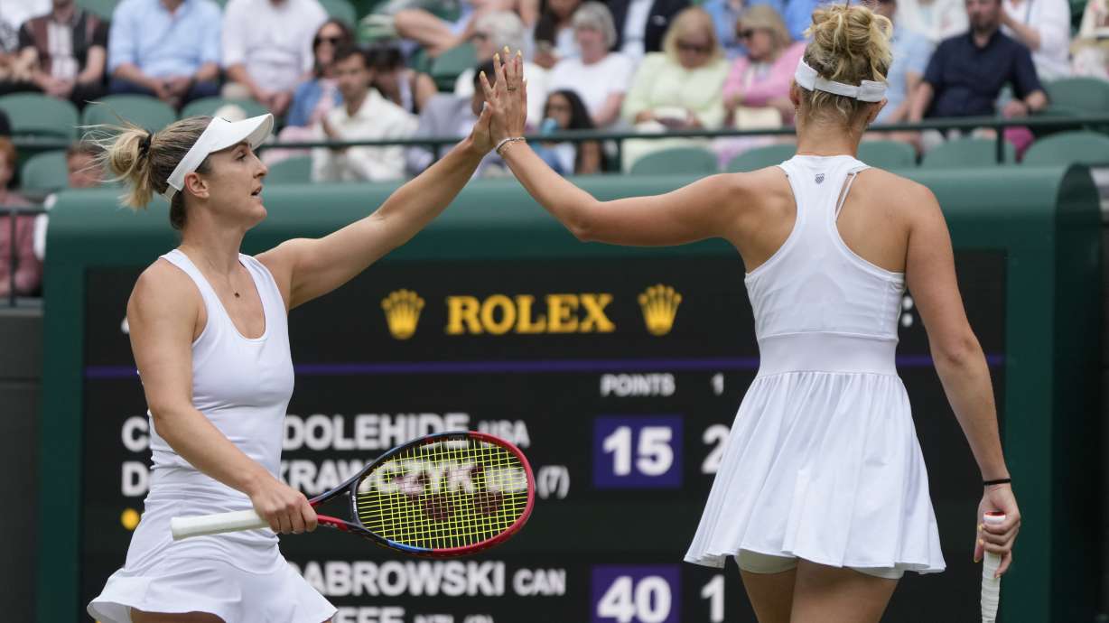 CORRECTS SPELLING OF LAST NAME TO ROUTLIFFE, NOT ROUTINE AS ORIGINALLY SENT - Gabriela Dabrowski of Canada, left, with playing partner Erin Routliffe of New Zealand, touch hands after winning a point as they play against Caroline Dolehide of the United States and Desirae Krawczyk of the United States during their semifinal doubles match at the Wimbledon tennis championships in London, Friday, July 12, 2024.