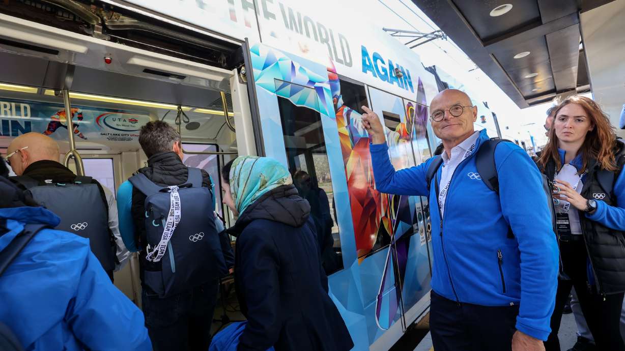 Karl Stoss, Future Host Commission for the Olympic Winter Games chair, points at a special Olympic-themed wrap on the outside of a TRAX train while boarding to tour proposed venues for the 2034 Games in Salt Lake City on April 10.