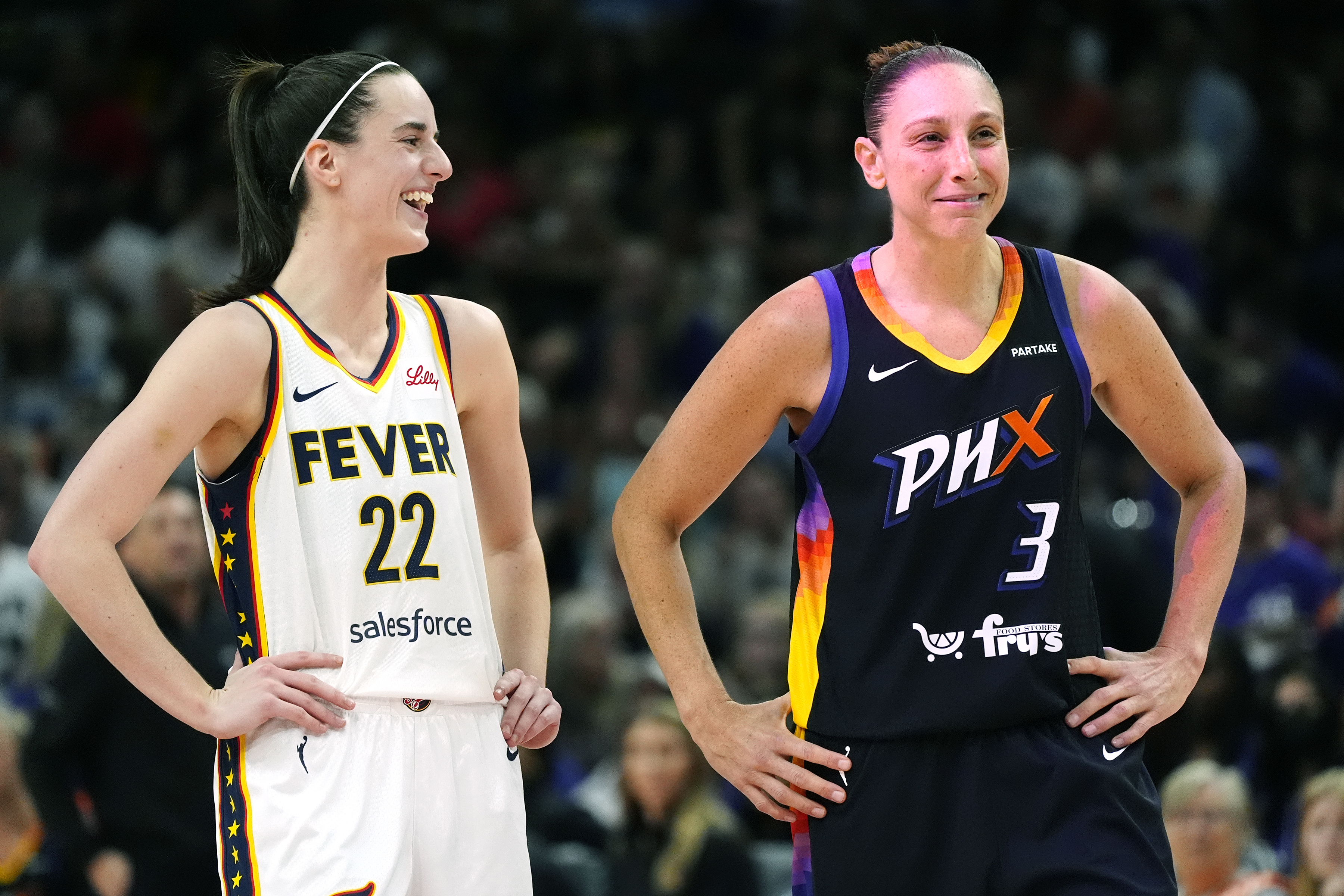 Indiana Fever guard Caitlin Clark (22) and Phoenix Mercury guard Diana Taurasi (3) laugh during the first half of a WNBA basketball game Sunday, June 30, 2024, in Phoenix.