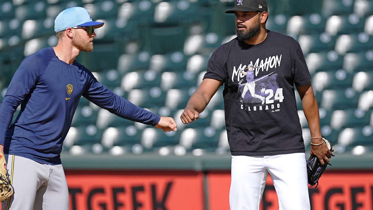 Milwaukee Brewers first baseman Jake Bauers, left, greets injured Colorado Rockies starting pitcher German Marquez before a baseball game Tuesday, July 2, 2024, in Denver.