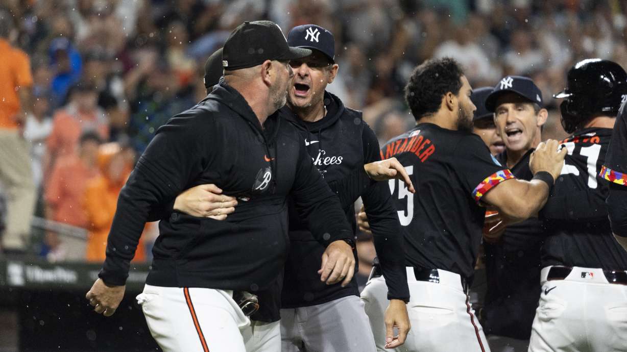 CORRECTS NAME TO ORIOLES MANAGER BRANDON HYDE - New York Yankees manager Aaron Boone, center, and Baltimore Orioles manager Brandon Hyde, left, argue after players cleared the benches during the ninth inning of a baseball game, Friday, July 12, 2024, in Baltimore.