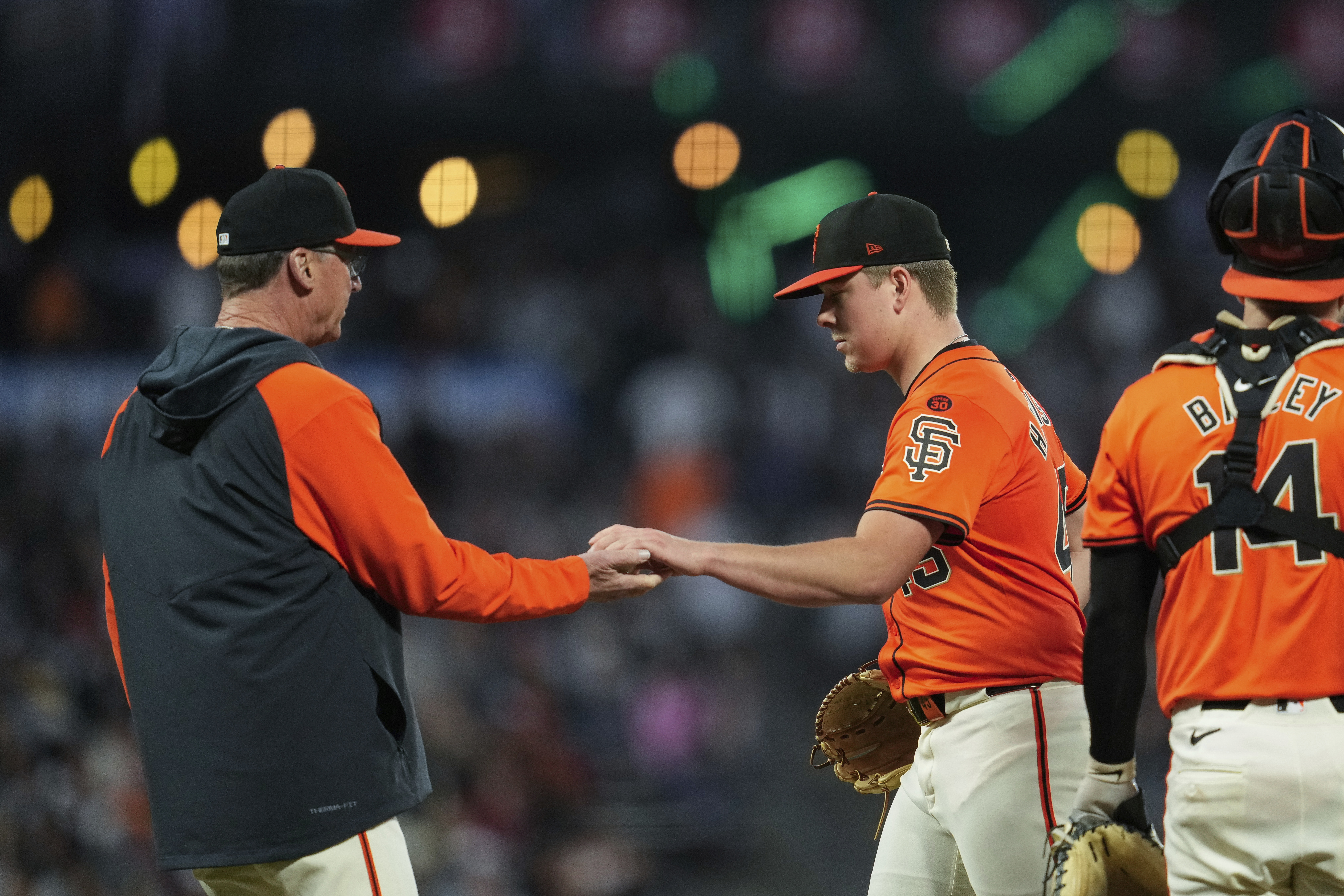 San Francisco Giants pitcher Kyle Harrison, second from right, hands the ball to manager Bob Melvin, left, as he exits during the sixth inning of a baseball game against the Minnesota Twins, Friday, July 12, 2024, in San Francisco. 