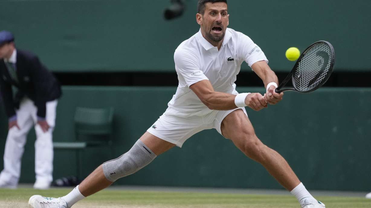 Novak Djokovic of Serbia plays a backhand return to Lorenzo Musetti of Italy during their semifinal match at the Wimbledon tennis championships in London, Friday, July 12, 2024.
