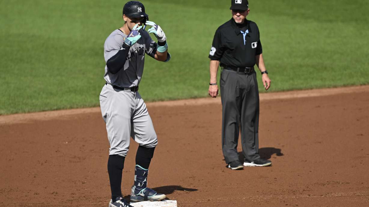 New York Yankees' Aaron Judge, left, gestures after hitting a double off Baltimore Orioles pitcher Grayson Rodriguez during the third inning of a baseball game, Saturday, July 13, 2024, in Baltimore.