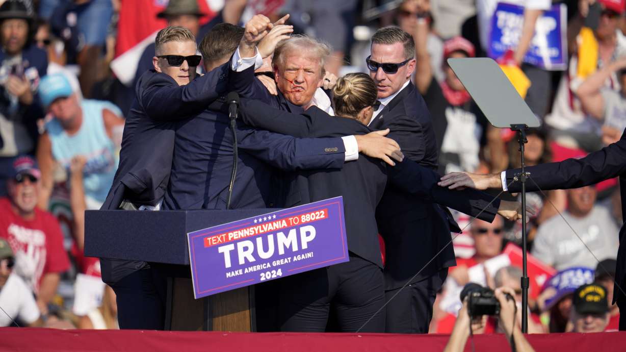 Republican presidential candidate former President Donald Trump is surrounded by U.S. Secret Service agents following a shooting at a campaign event in Butler, Pennsylvania, on Saturday.