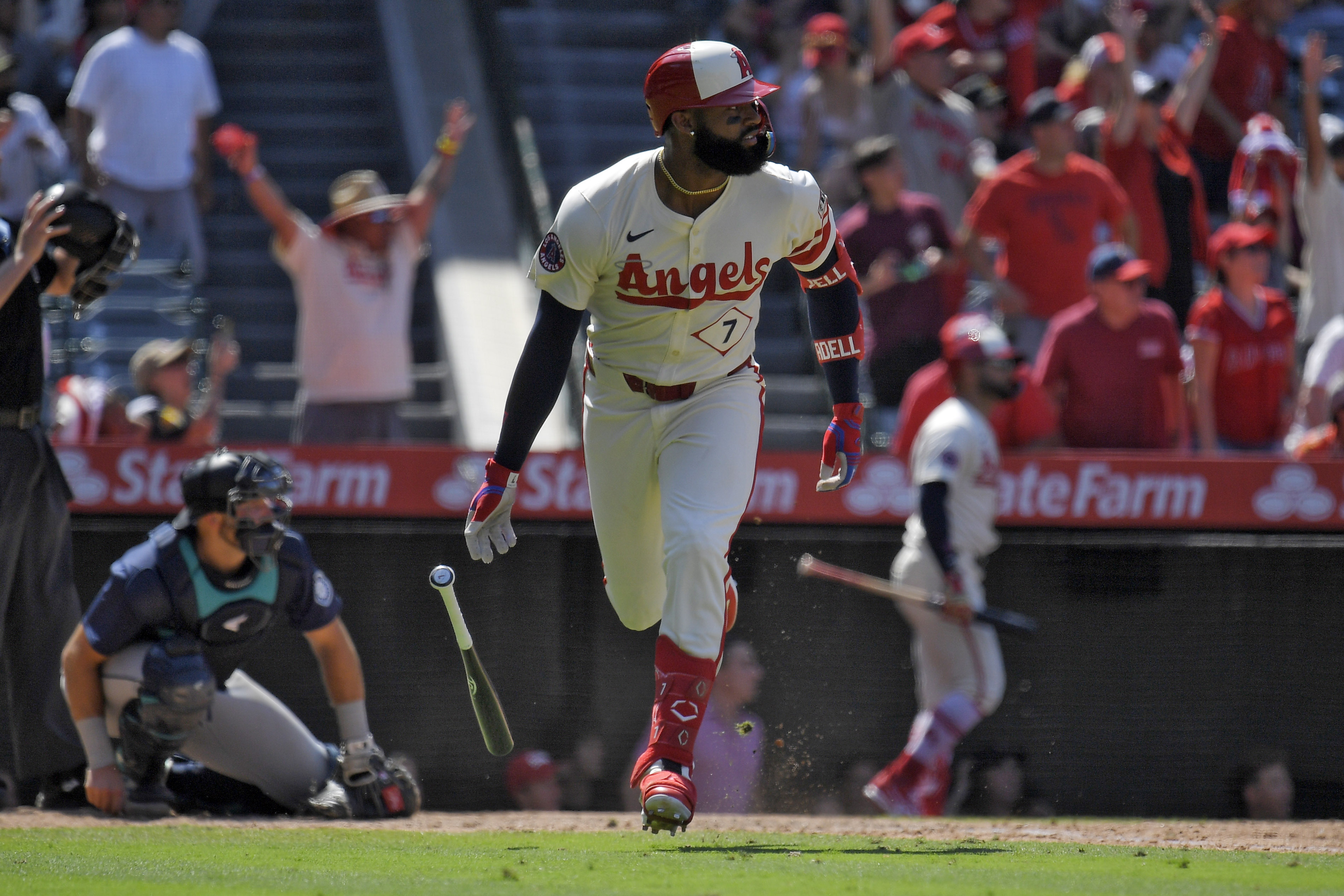 Los Angeles Angels' Jo Adell, right, heads to first for a three-run home run as Seattle Mariners catcher Cal Raleigh kneels at the plate during the eighth inning of a baseball game Sunday, July 14, 2024, in Anaheim, Calif. 
