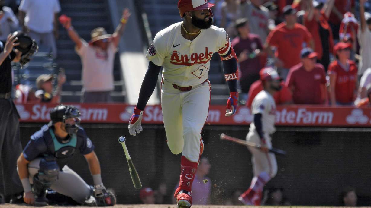 Los Angeles Angels' Jo Adell, right, heads to first for a three-run home run as Seattle Mariners catcher Cal Raleigh kneels at the plate during the eighth inning of a baseball game Sunday, July 14, 2024, in Anaheim, Calif.