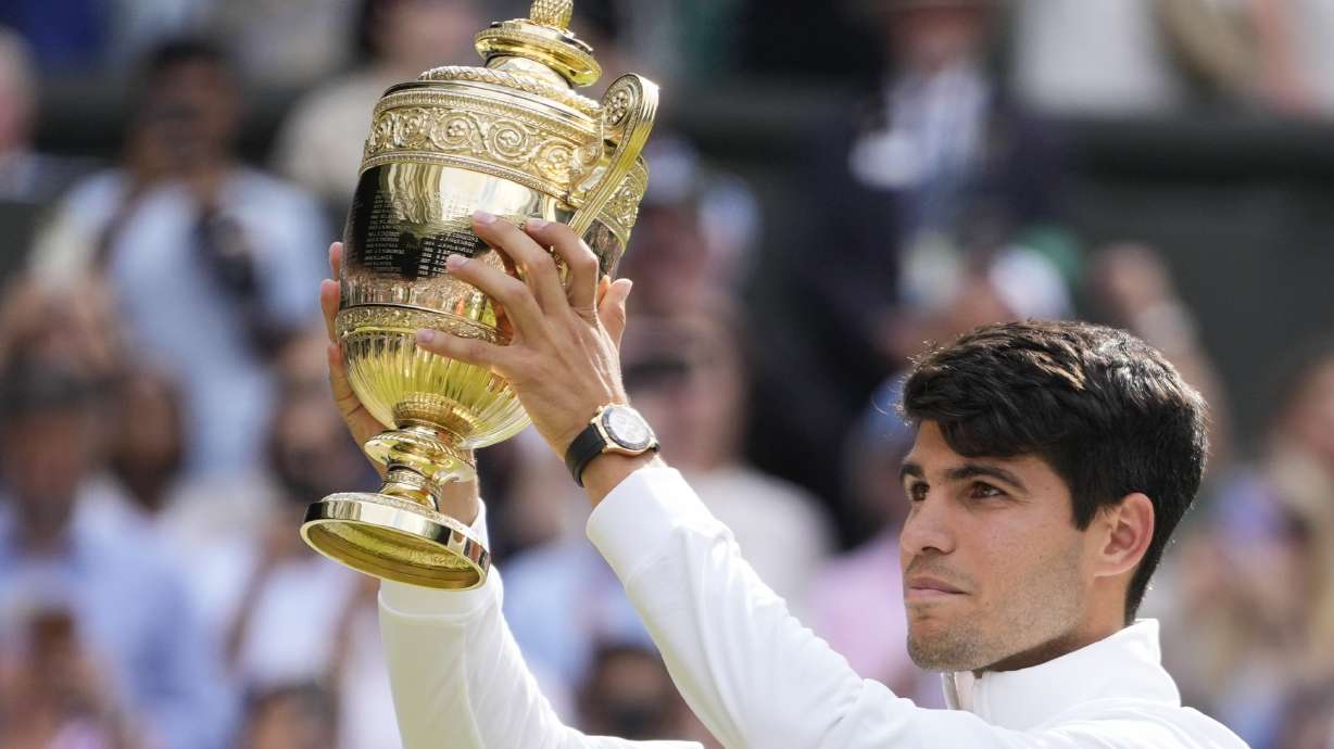 Carlos Alcaraz of Spain holds his trophy aloft after defeating Novak Djokovic of Serbia in the men's singles final at the Wimbledon tennis championships in London, Sunday, July 14, 2024.