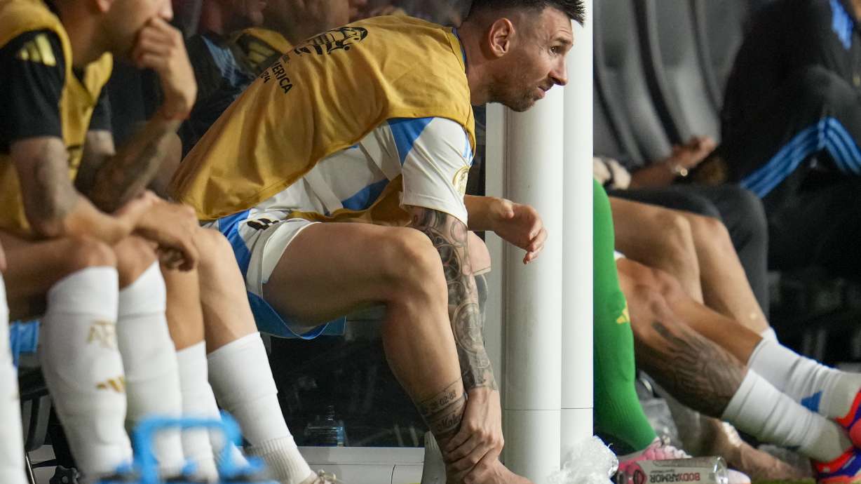Argentina's Lionel Messi touches his ankle sitting at the bench during a Copa America soccer final match against Colombia in Miami Gardens, Fla., Sunday, July 14, 2024.