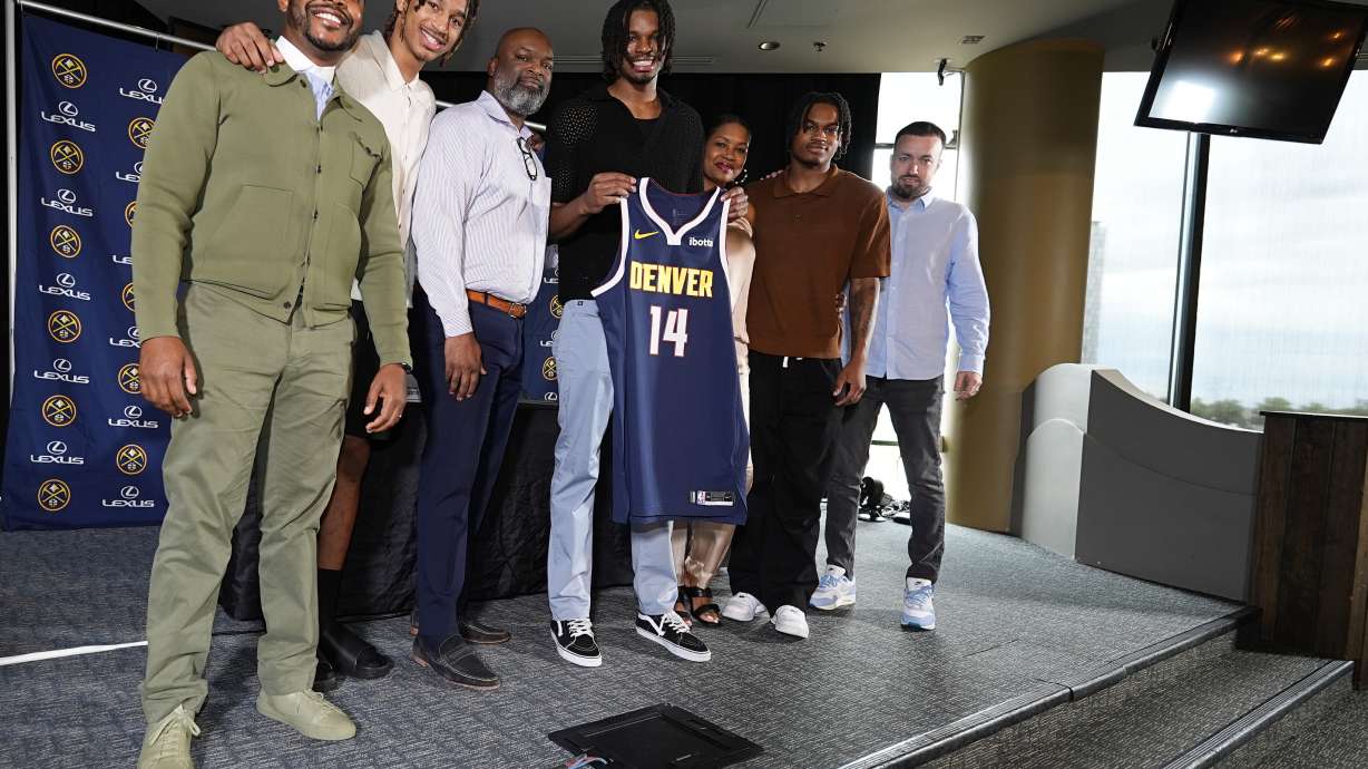 Denver Nuggets 2024 first-round draft pick DaRon Holmes II, center, holds up his jersey for a photograph with, from left, business manager Mitch Brown, brother Cameron Holmes, father DaRon, Sr., mother Tomika, brother Quintyn and agent Aaron Reilly during an NBA basketball news conference Monday, July 1, 2024, in Denver.