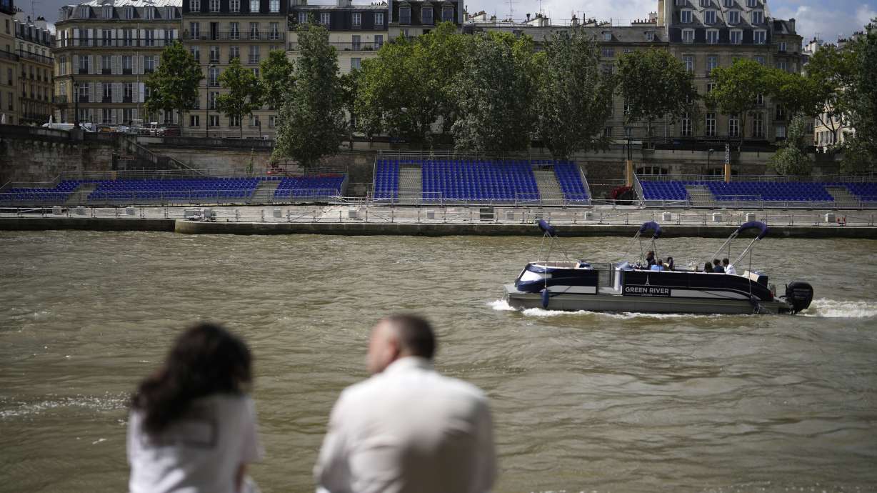 FILE - People sit along the Seine River with stands installed on its banks, July 4, 2024, in Paris.