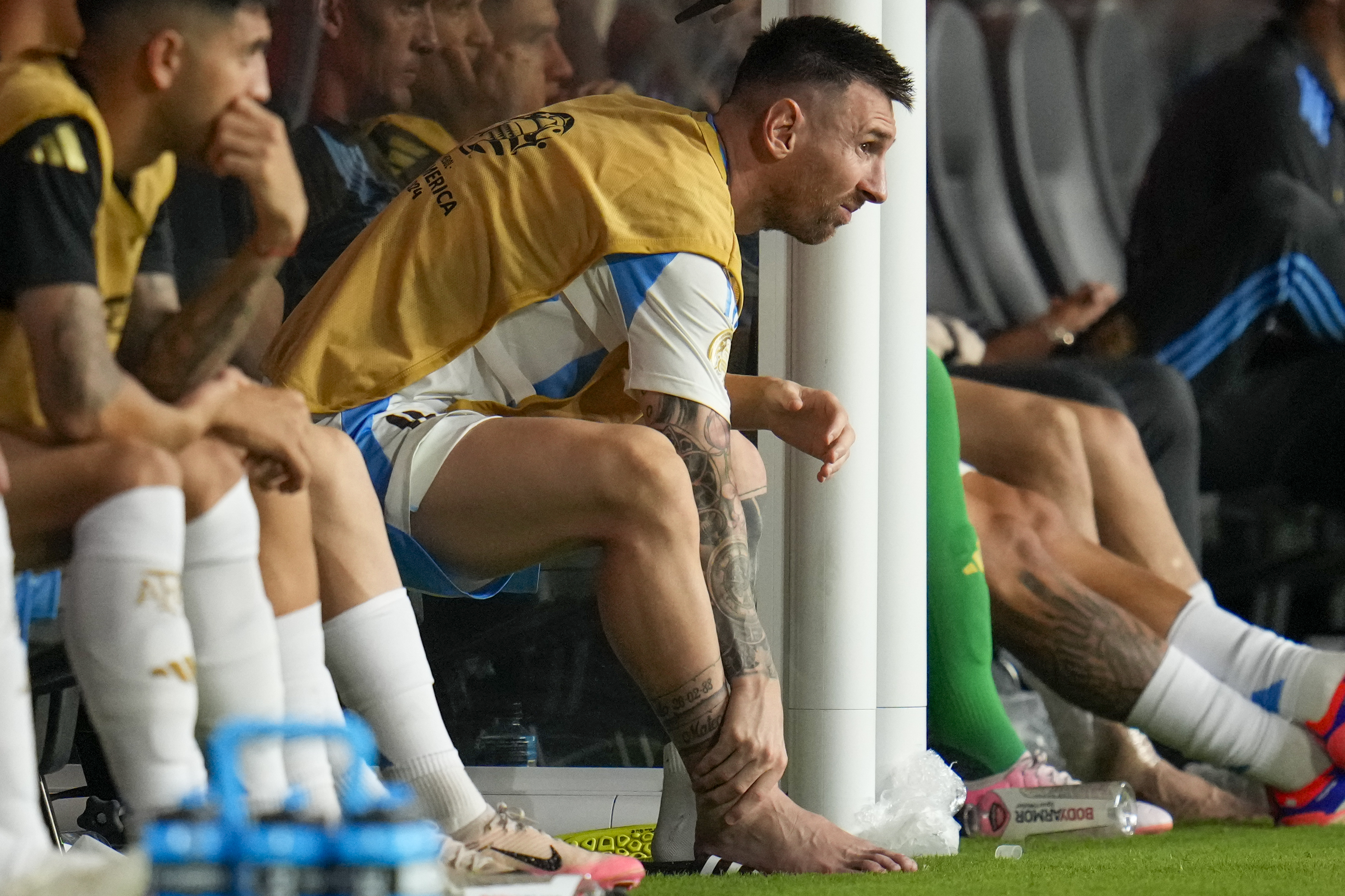 Argentina's Lionel Messi touches his ankle sitting at the bench during a Copa America soccer final match against Colombia in Miami Gardens, Fla., Sunday, July 14, 2024.