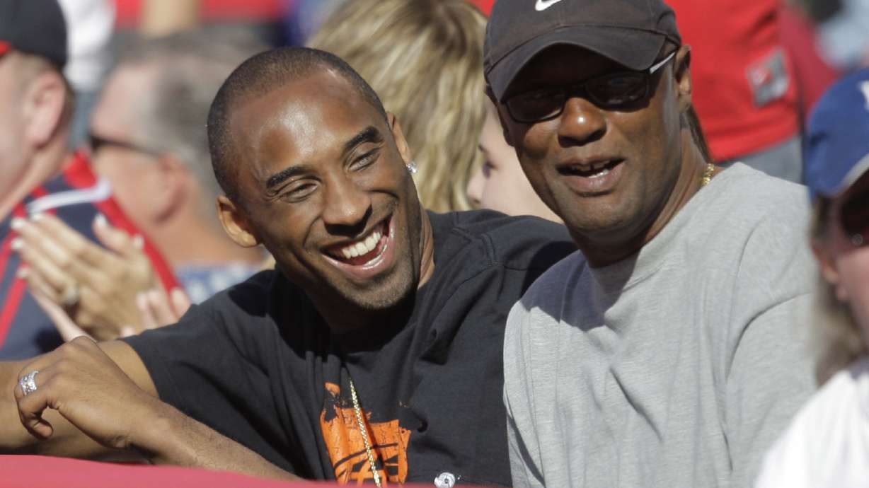 FILE - Los Angeles Lakers' Kobe Bryant, left, talks to his father, Joe, as they watch a baseball game between the Los Angeles Angels and the Los Angeles Dodgers in Anaheim, Calif., Sunday, June 21, 2009. Joe “Jellybean” Bryant has died, his alma mater announced Tuesday, July 16, 2024. Joe Bryant, who spent eight seasons in the NBA with three different franchises, was 69. The Philadelphia Inquirer, citing La Salle coach Fran Dunphy, reported that Joe Bryant recently had a massive stroke.