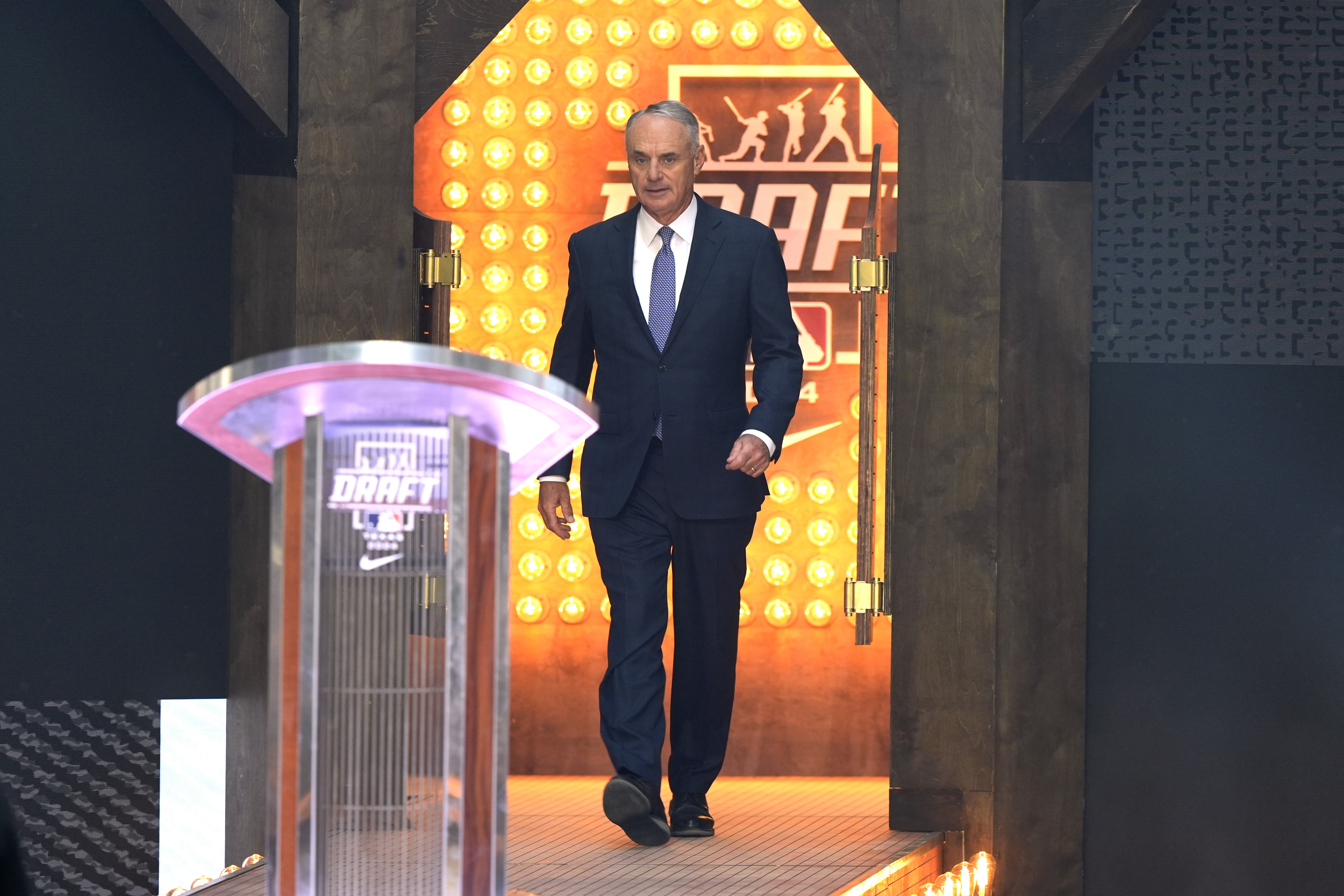 Major League Baseball Commissioner Rob Manfred walks up to the podium during the MLB baseball draft in Fort Worth, Texas, Sunday, July 14, 2024. 