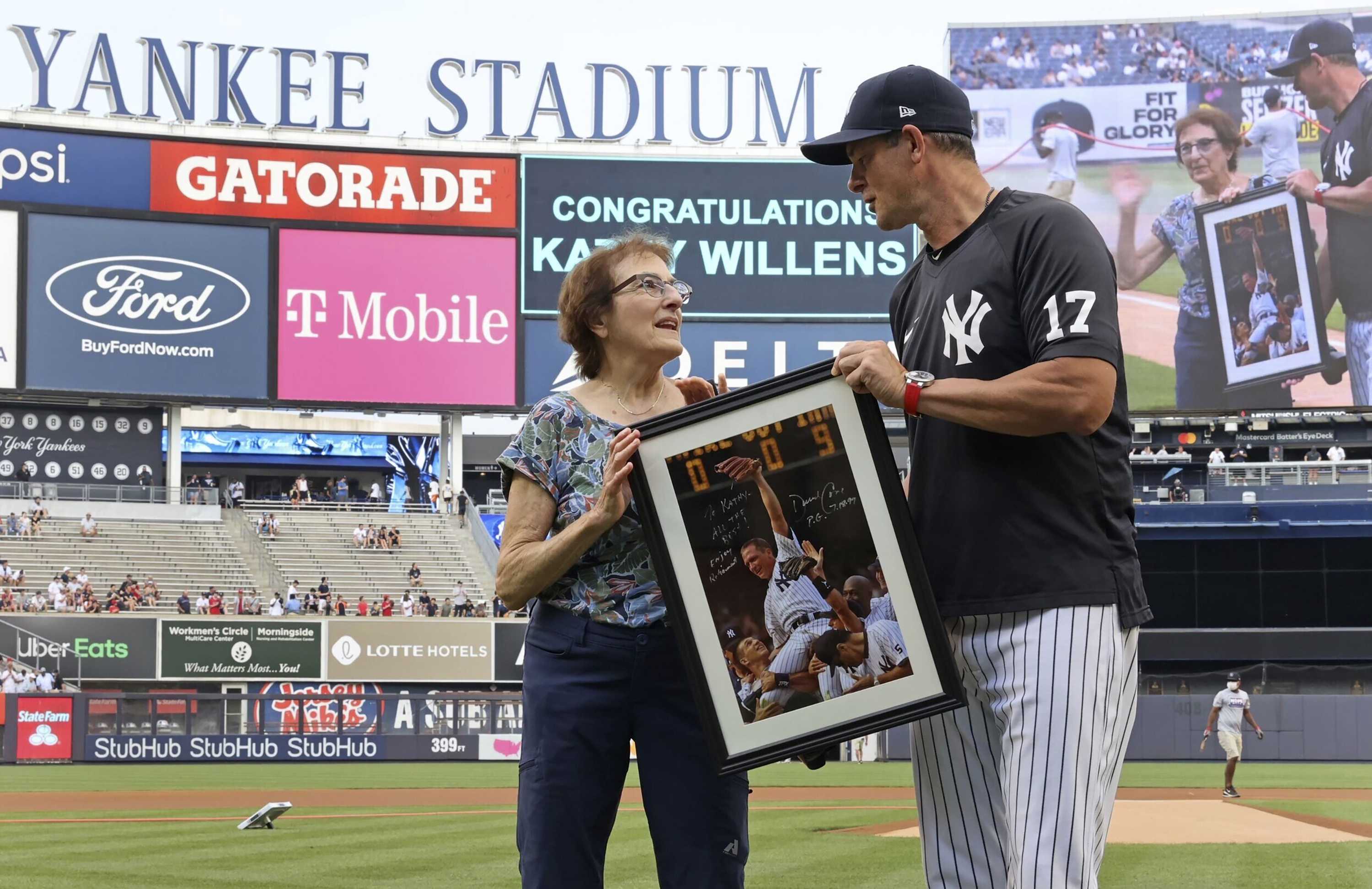 Yankees' Aaron Boone presents an autographed picture to Kathy Willens on June 28, 2021, in New York, of her picture of New York Yankees pitcher David Cone after Cone threw a perfect game. 
