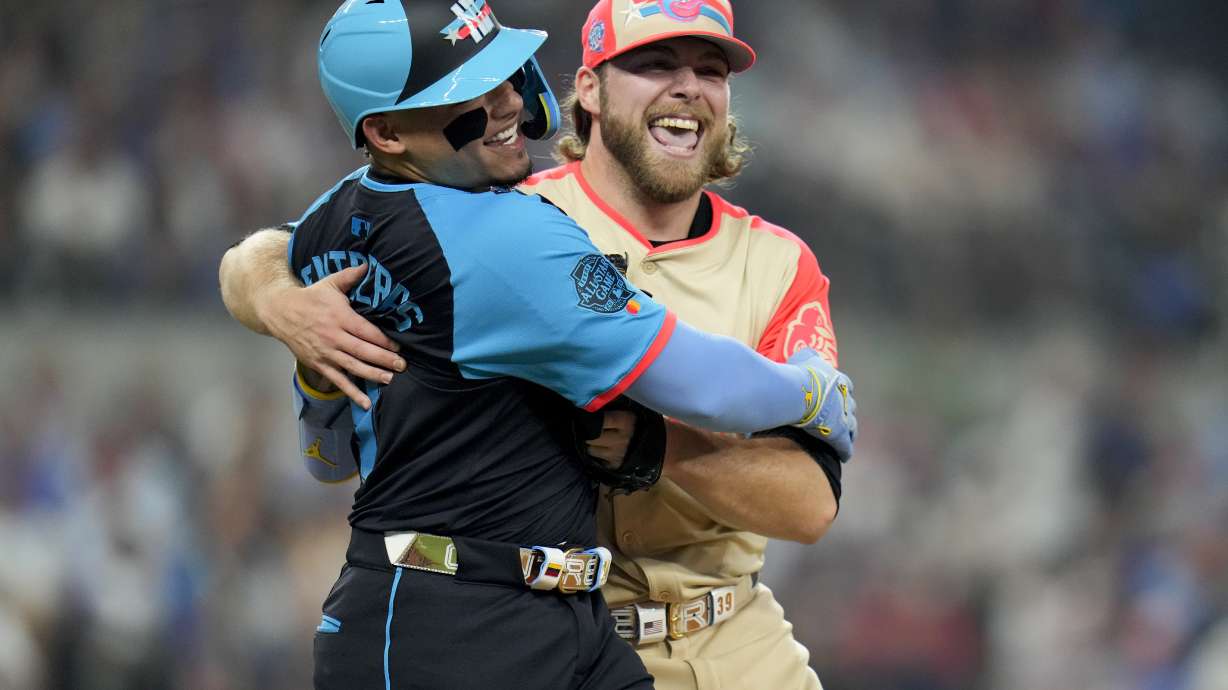 American League starting pitcher Corbin Burnes, of the Baltimore Orioles, right, hugs National League's William Contreras, of the Milwaukee Brewers, after an out on a ground ball by Contreras in the first inning during the MLB All-Star baseball game, Tuesday, July 16, 2024, in Arlington, Texas.