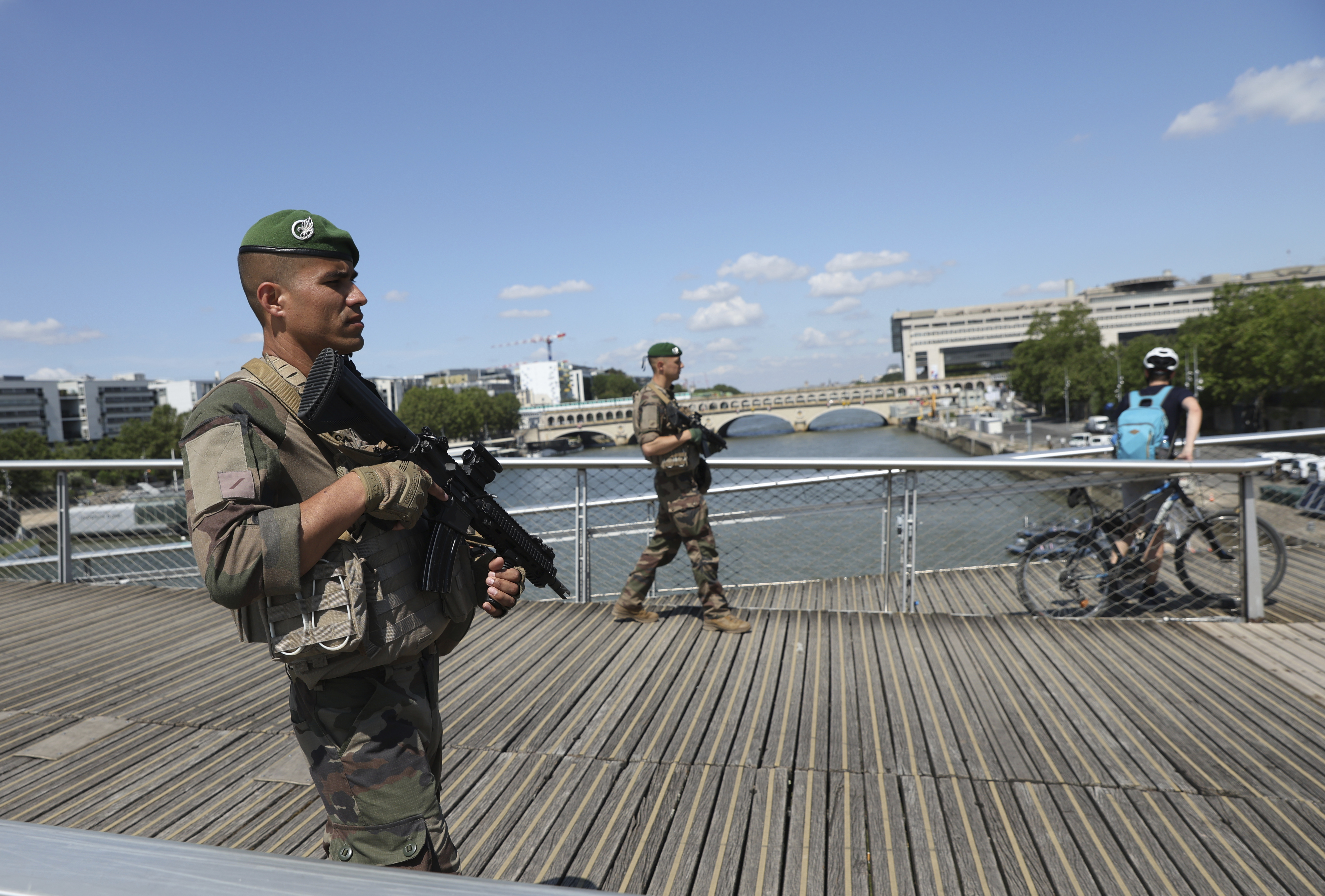 Soldiers patrol on a footbridge over the Seine river, Wednesday, July 17, 2024 in Paris. France's armed forces held a demonstration of the security measures planned on the River Seine, both in and out of the water, to make it safe for athletes and spectators during the opening ceremony of the Paris Olympics. Organizers have planned a parade of about 10,000 athletes through the heart of the French capital on boats on the Seine along a 6-kilometer (3.7-mile) route at sunset on July 26.