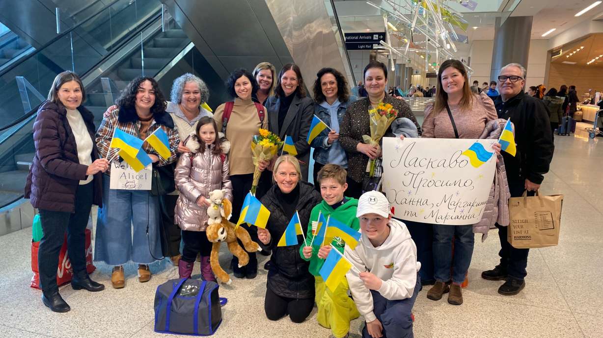 WelcomeNST team poses with Marianna, Hanna, Margot and their cat, Alice, at the Salt Lake City International Airport on the day they arrived as refugees to the U.S. in Jan. 2023. The team held Ukrainian flags and goodie bags for the Ukrainian women and 8-year-old Margot.