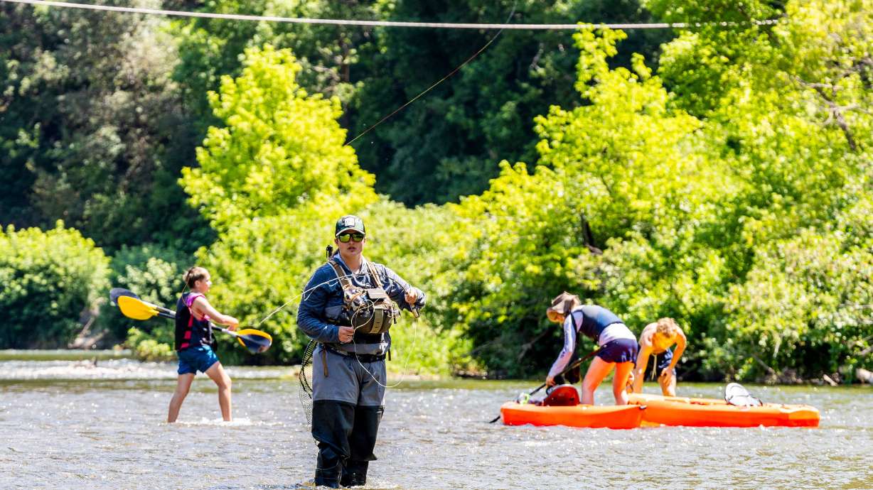 Kristen Almond, of Ashville, N.C., fishes along the Provo River near Vivian Park as kayakers make their way past in Provo Canyon on Wednesday.