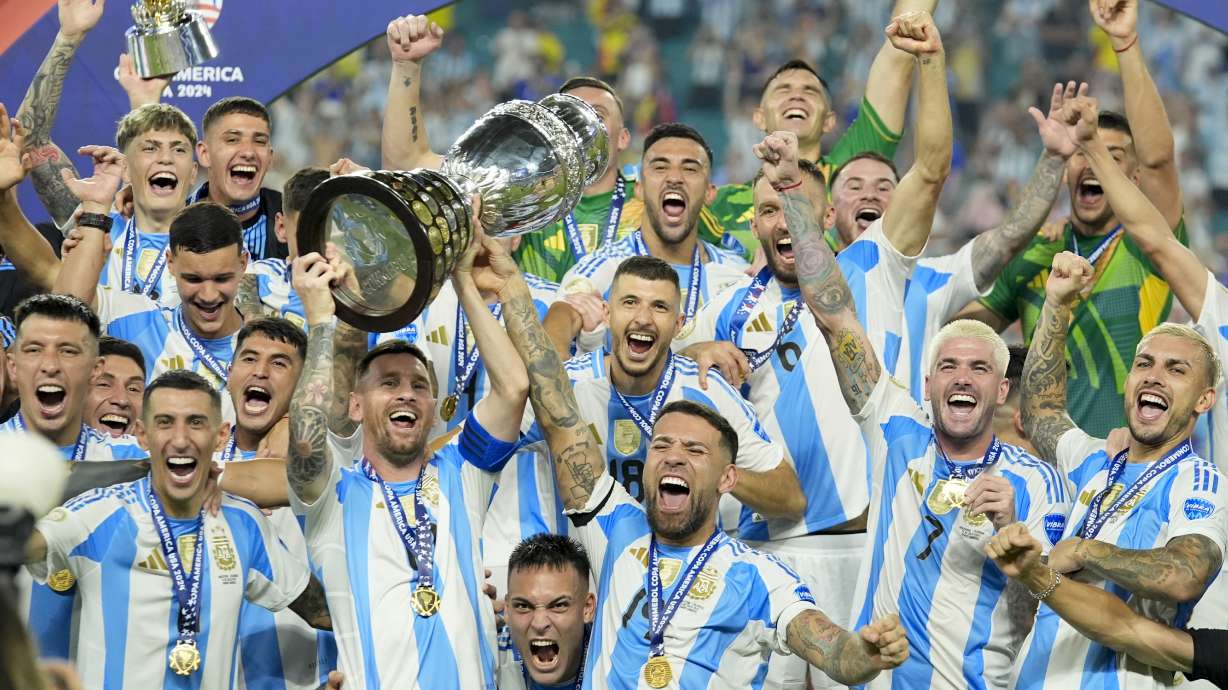 Argentina's Lionel Messi holds the trophy as celebrating with teammates after defeating Colombia in the Copa America final soccer match in Miami Gardens, Fla., Monday, July 15, 2024.