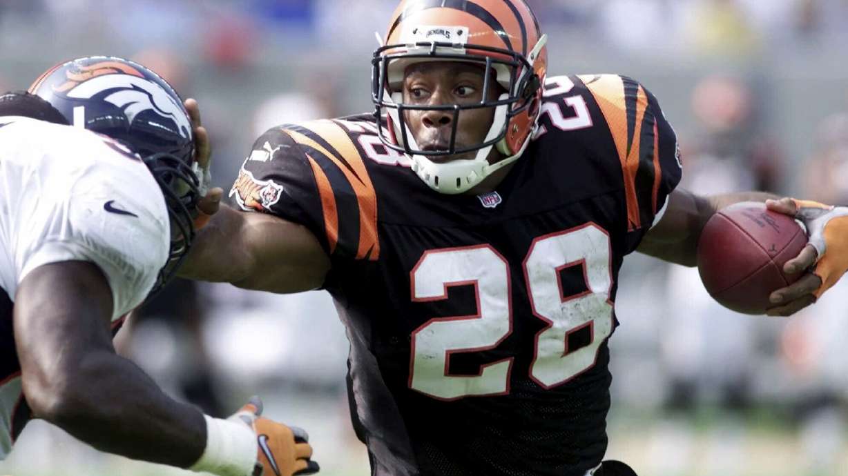 FILE - Cincinnati Bengals running back Corey Dillon (28) pushes away Denver Broncos defender Al Wilson, left, in the first half Sunday, Oct. 22, 2000, in Cincinnati. The Cincinnati Bengals are adding running back Corey Dillon and nose tackle Tim Krumrie to the team's Ring of Honor this fall.