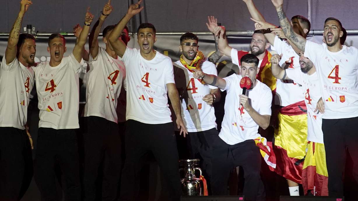 Spain's team captain Alvaro Morata, with the microphone, introduces player Rodri, center, to the fans during celebrations of the Spanish team's European soccer championship title on a stage at Cibeles square in Madrid, Monday, July 15, 2024. Spain defeated England in the final of the Euro 2024 soccer tournament in Berlin on Sunday evening.