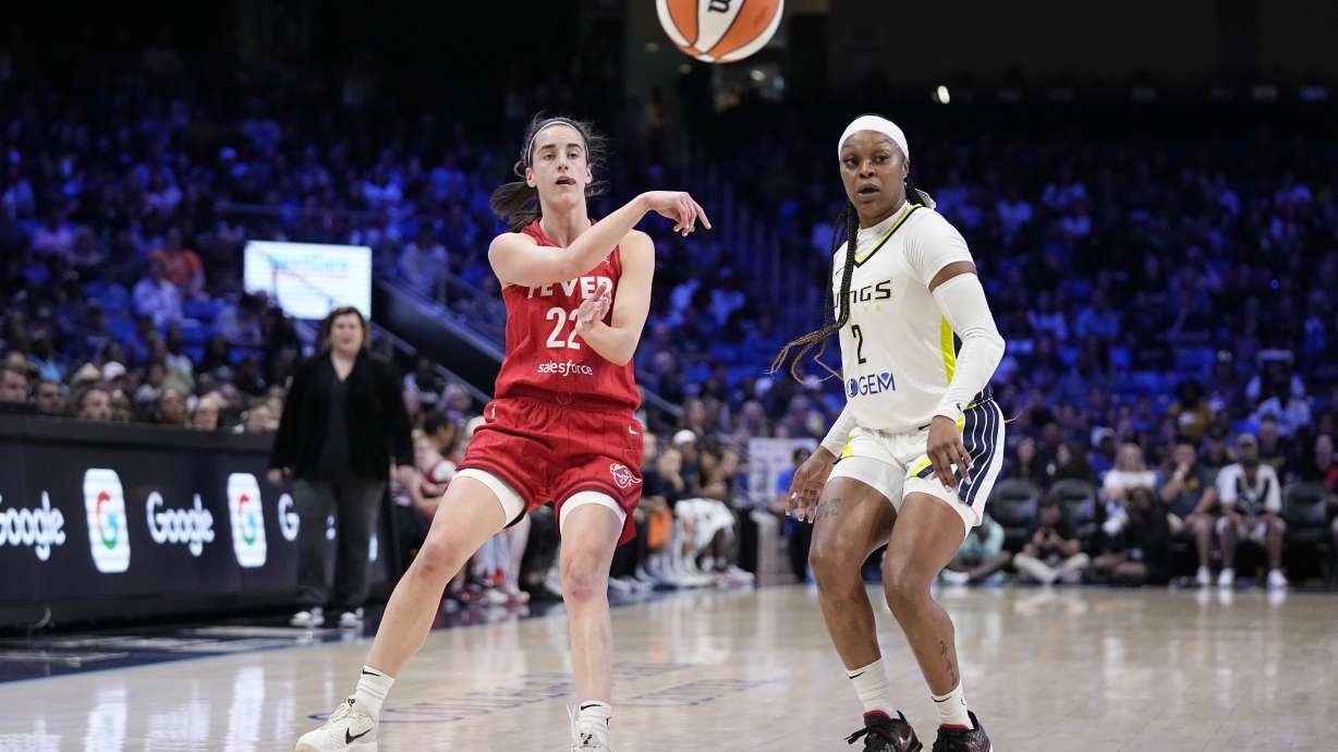 Indiana Fever's Caitlin Clark (22) makes a pass as Dallas Wings' Odyssey Sims (2) defends in the first half of a WNBA basketball game Wednesday, July 17, 2024, in Arlington, Texas.