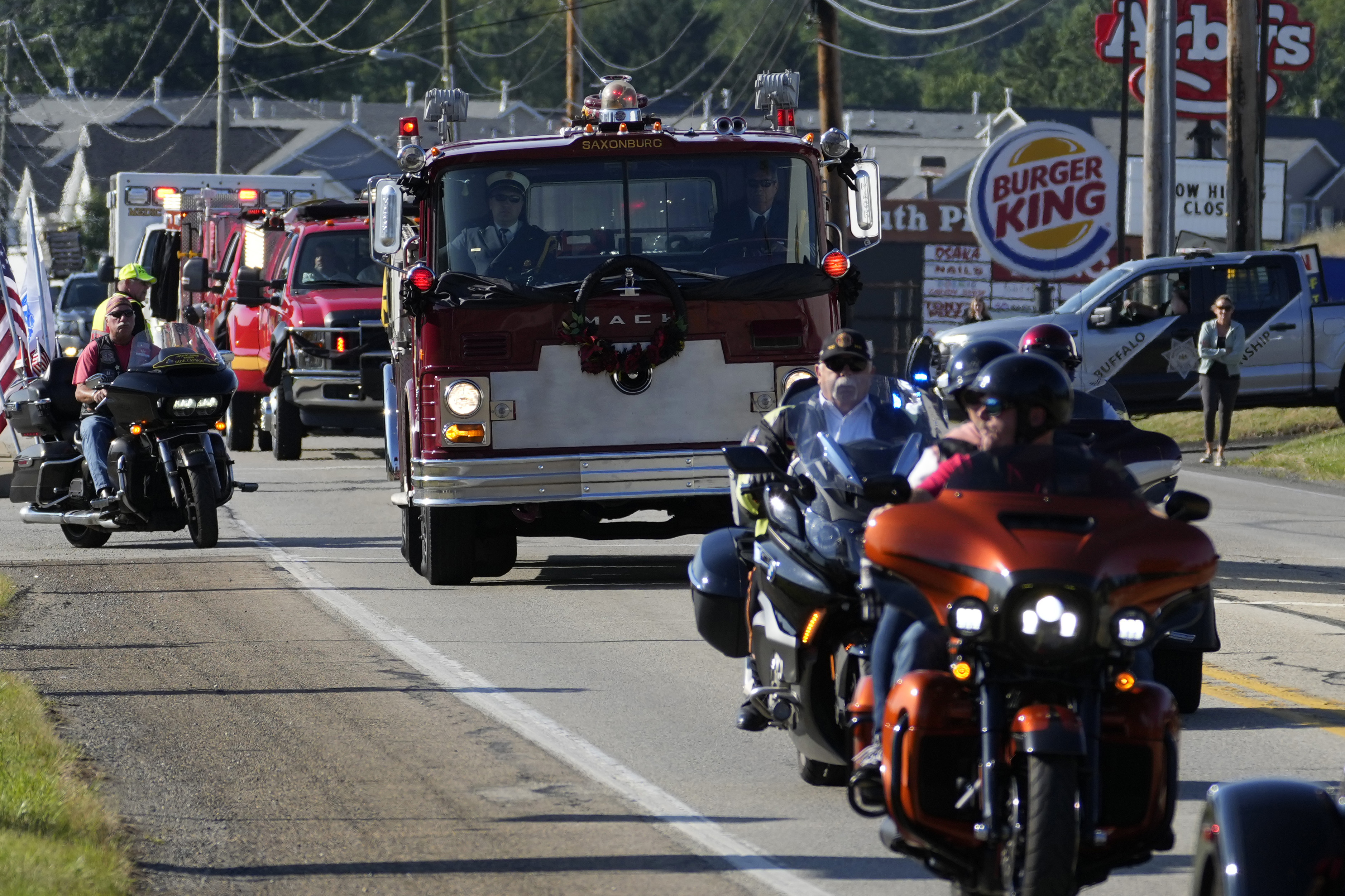 The funeral procession for Corey Comperatore passes, Friday, in Sarver, Pennsylvania. Comperatore, a former fire chief, was shot and killed while attending a weekend rally for former President Donald Trump.