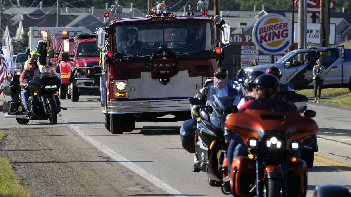 The funeral procession for Corey Comperatore passes, Friday, in Sarver, Pennsylvania. Comperatore, a former fire chief, was shot and killed while attending a weekend rally for former President Donald Trump.