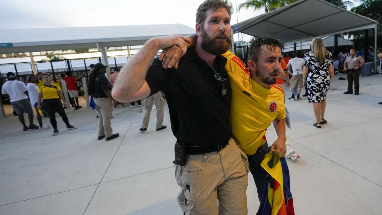 A security agent assist a fan who was waiting to enter the stadium prior to the Copa America final soccer match between Argentina and Colombia, in Miami Gardens, Fla., Sunday, July 14, 2024.