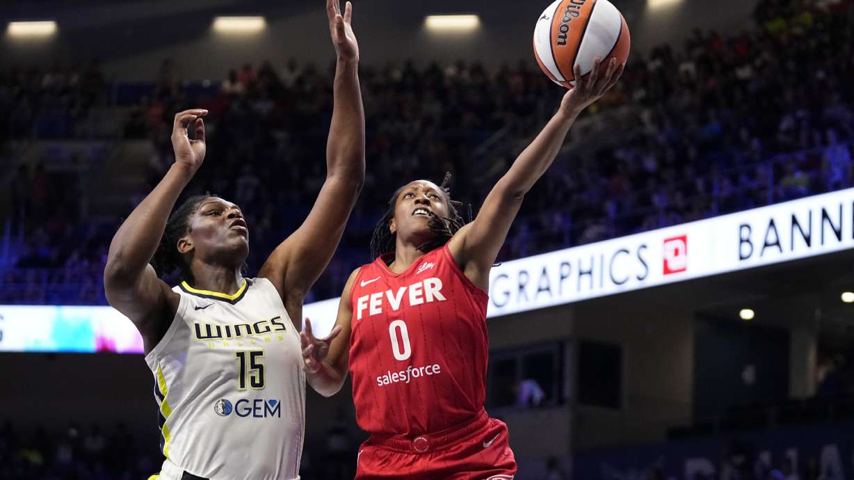 Indiana Fever's Kelsey Mitchell (0) leaps to the basket to take a shot as Dallas Wings' Teaira McCowan (15) defends in the first half of a WNBA basketball game Wednesday, July 17, 2024, in Arlington, Texas.