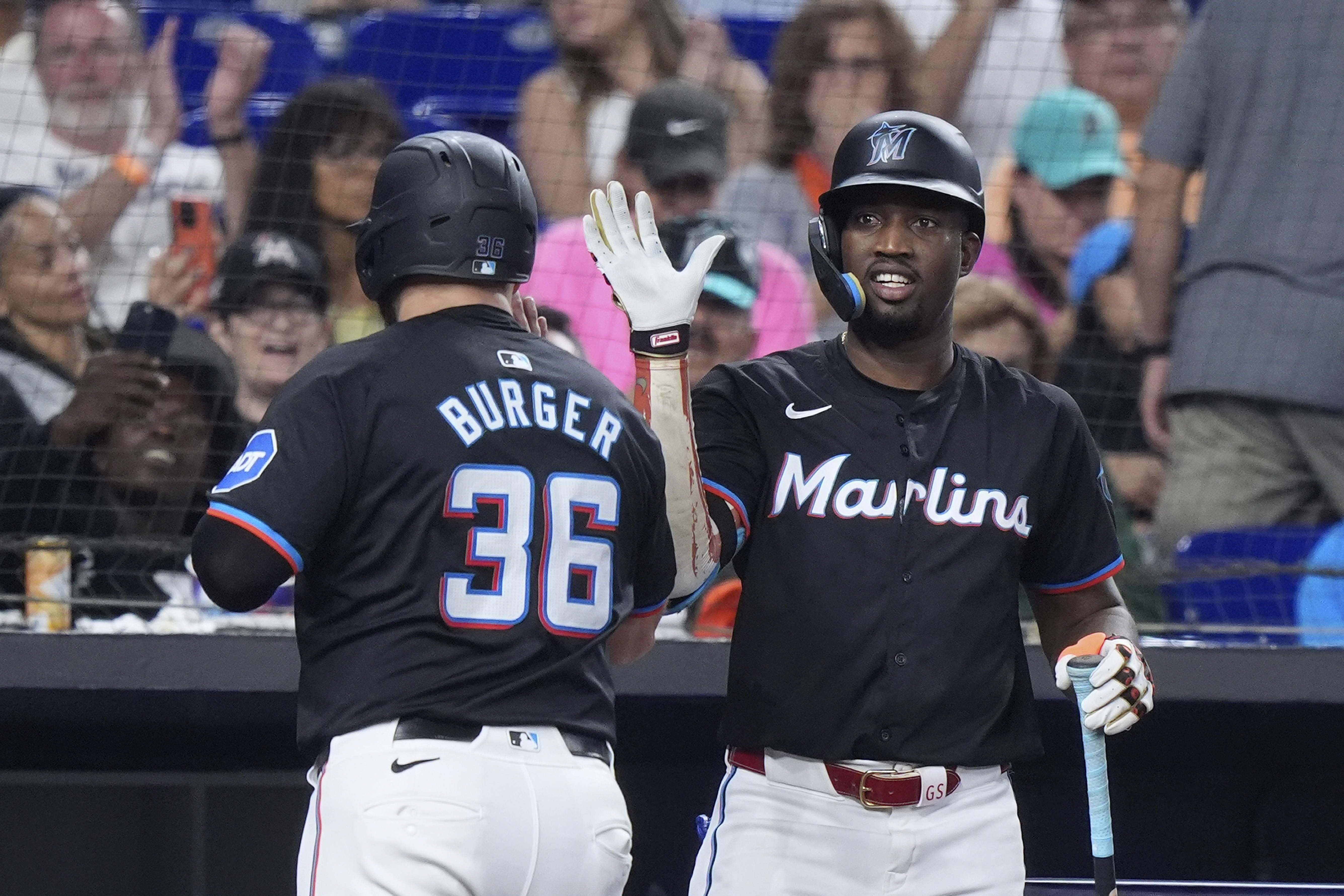 Miami Marlins' Jake Burger (36) is congratulated by Jesús Sánchez after Burger scored on a single by Josh Bell during the third inning of a baseball game against the New York Mets, Friday, July 19, 2024, in Miami. 