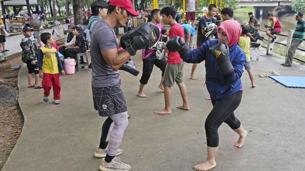 Rani Miranti, right, practices martial arts with Rizal Zulmi, a professional MMA fighter, at a public park in Jakarta, Indonesia, Sunday, July 7, 2024.