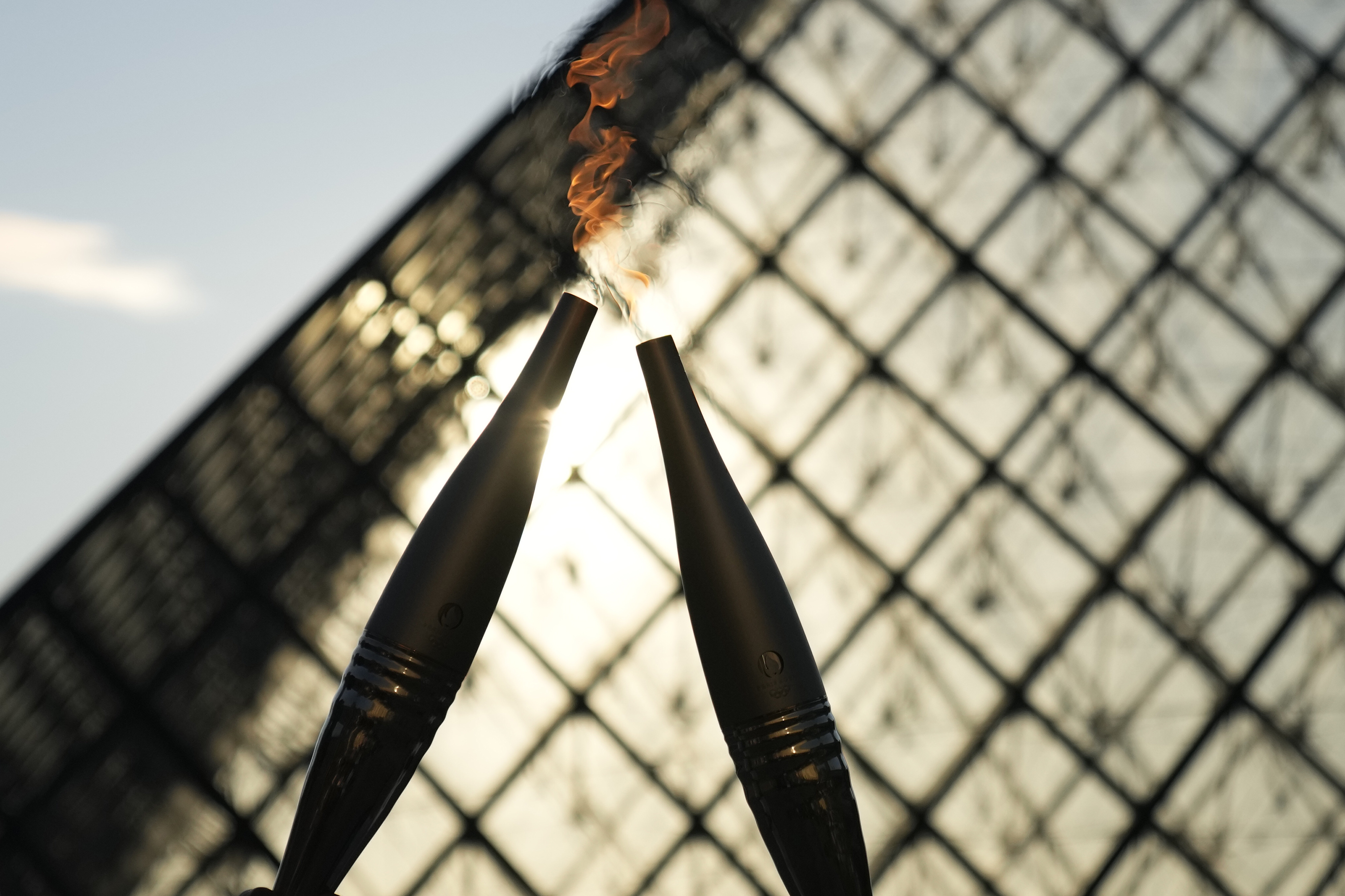 FILE -The Olympic torch is seen during a relay in the courtyard of the Louvre museum Sunday, July 14, 2024 in Paris. French prosecutors say a 19-year-old man, who has made threats on social media and was suspected of wanting to target the Olympic torch relay, was sentenced to two years in prison.