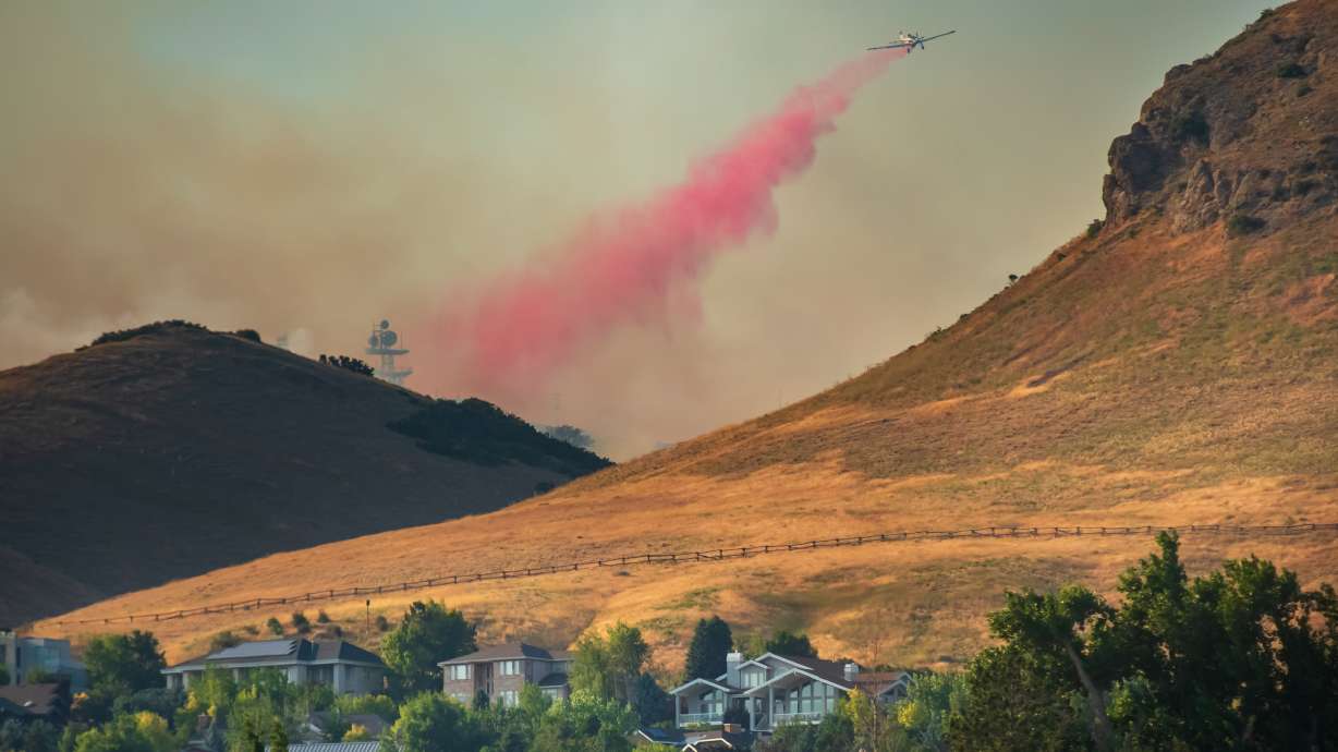 A plane dumps fire retardant on the Sandhurst Fire in the foothills near Ensign Peak in Salt Lake City on July 20, 2024. The city is considering a new fire code for homes and properties next to areas most prone to wildfires to comply with a new state law.
