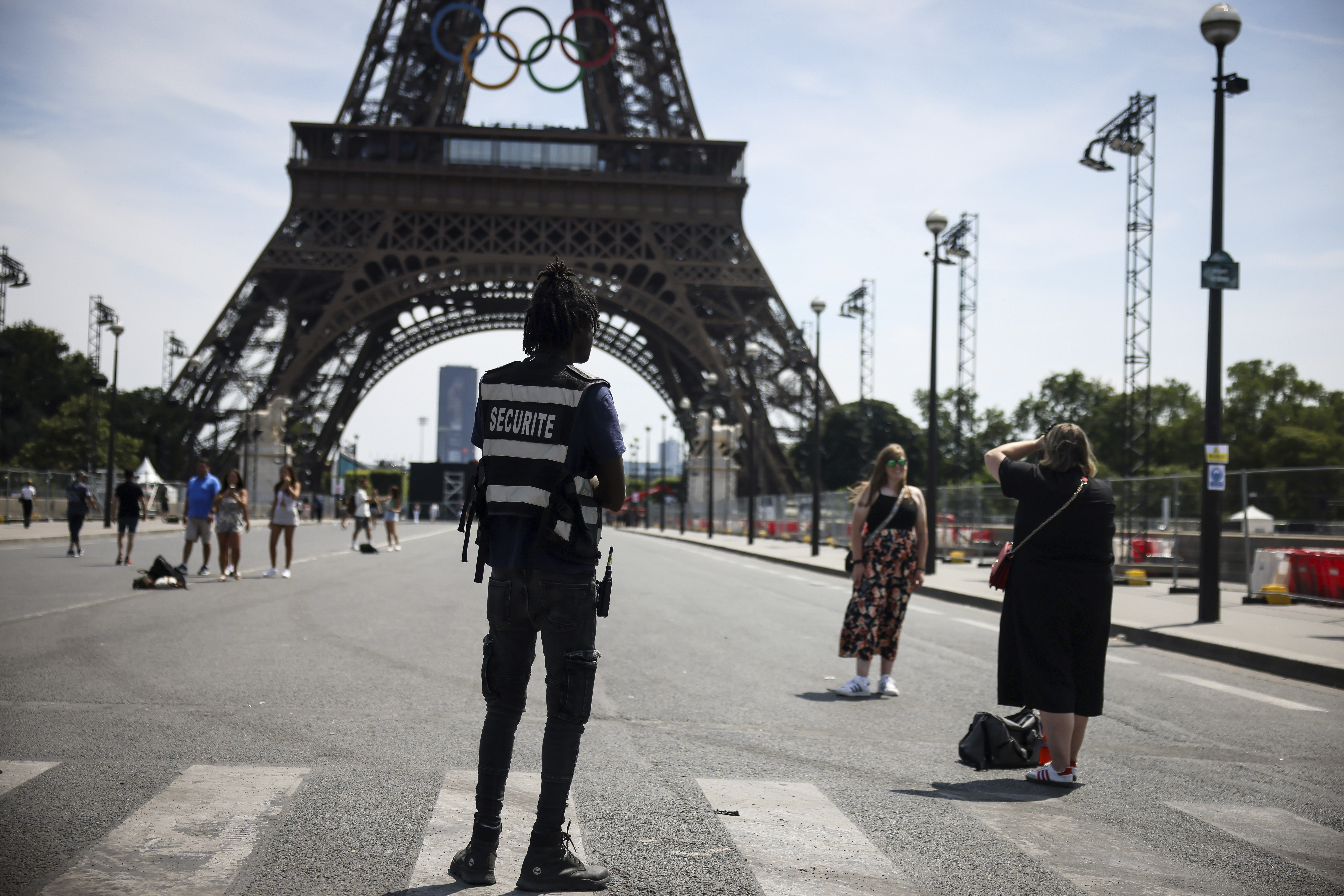 A security officer watches people taken photographs in front of the Eiffel Tower at the 2024 Summer Olympics, Saturday, July 20, 2024, in Paris, France. 