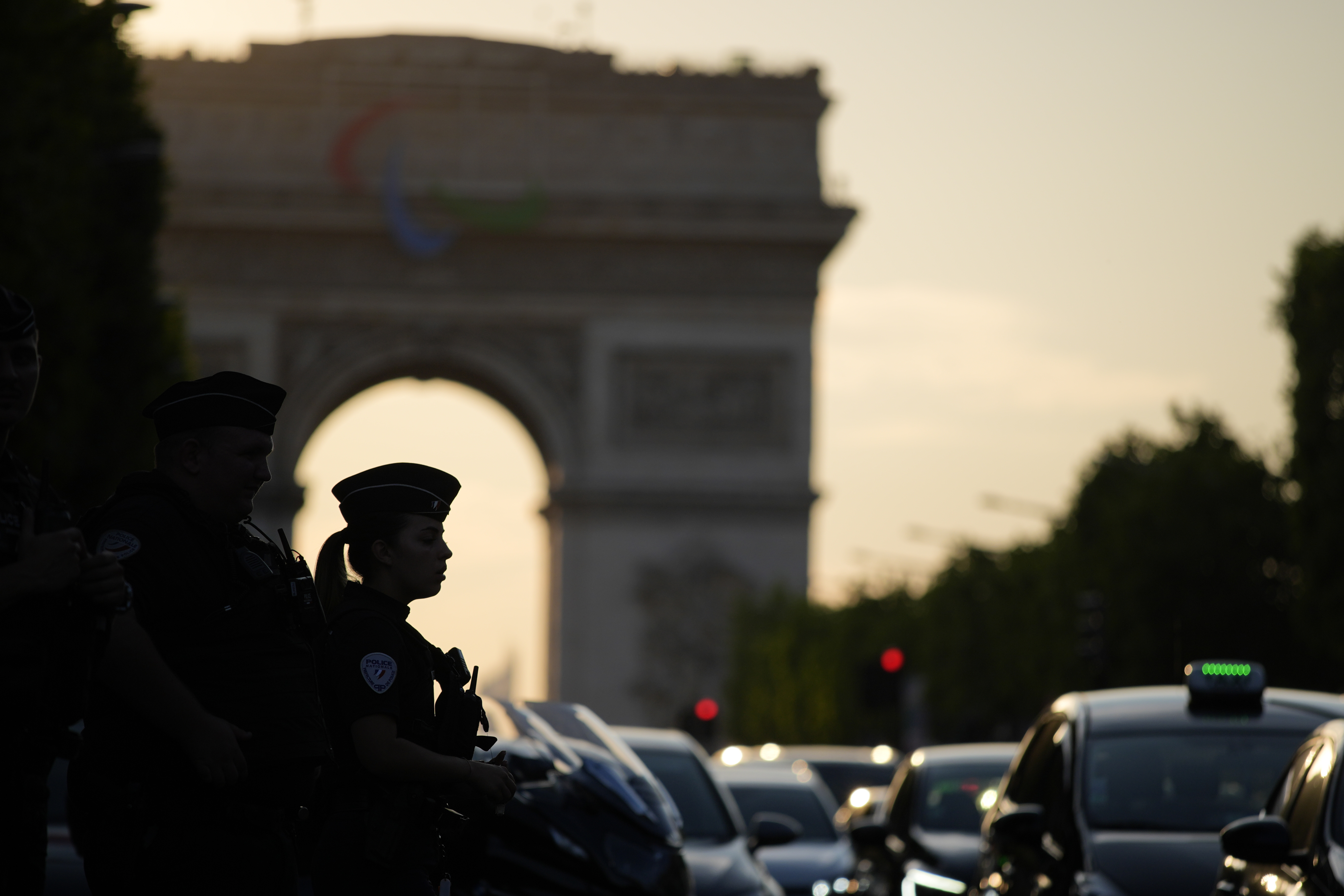 A police officer is silhouetted by the Arc de Triomphe after a stabbing near the Champs-Elysees avenue, Thursday, July 18, 2024, in Paris. 
