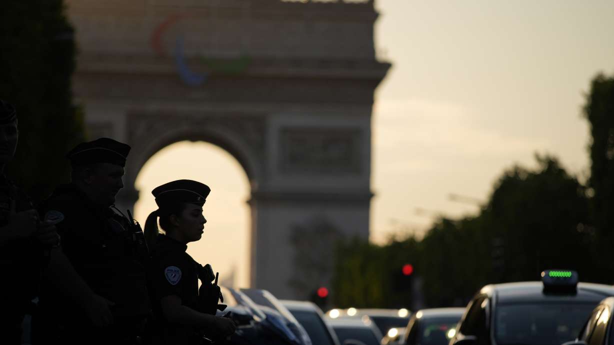 A police officer is silhouetted by the Arc de Triomphe after a stabbing near the Champs-Elysees avenue, Thursday, July 18, 2024, in Paris.