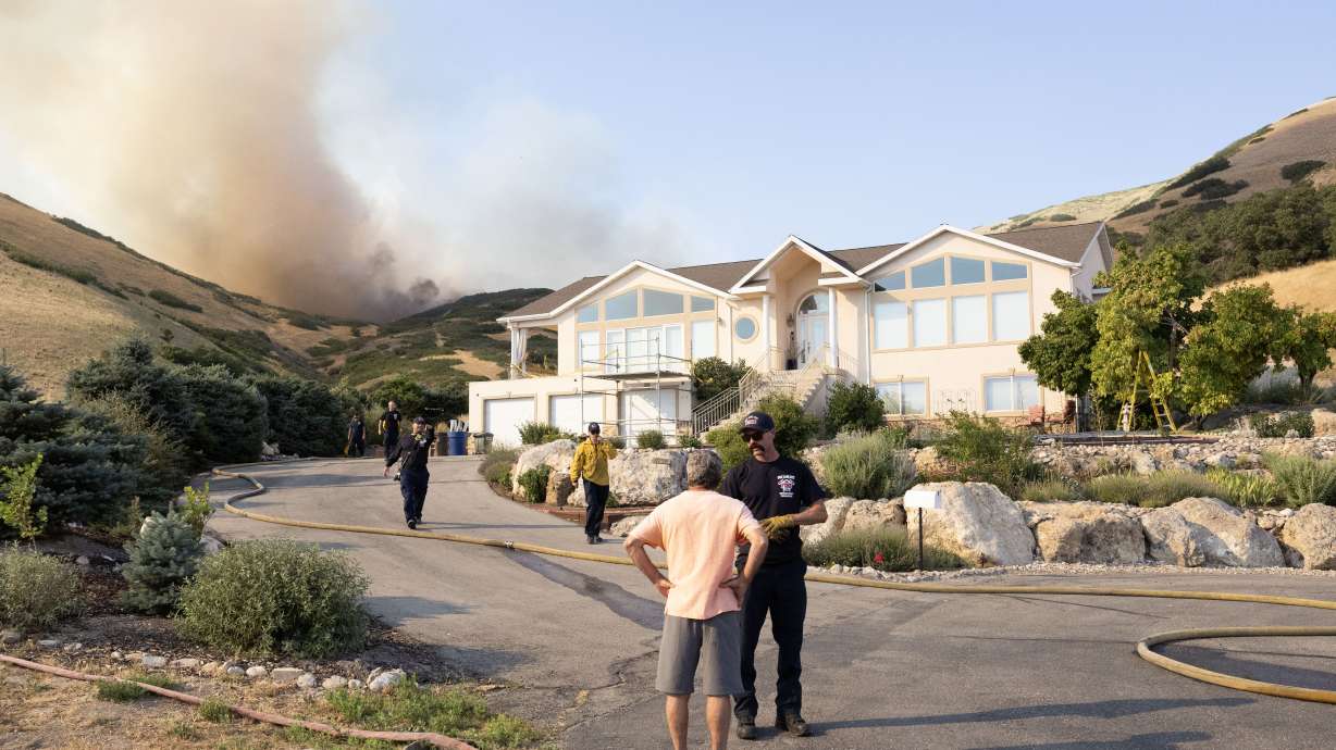 A Salt Lake City firefighter tells a local resident to evacuate while the flames from a wildfire burning around Ensign Peak grow closer to his home on Twickenham Drive in Salt Lake City on Saturday.