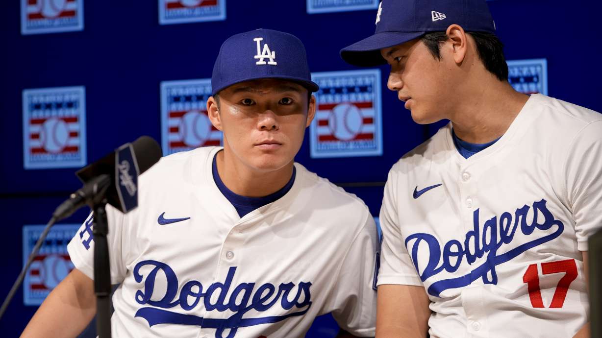 Los Angeles Dodgers pitcher Yoshinobu Yamamoto, left, leans in to speak with designated hitter Shohei Ohtani during a news conference announcing a planned Baseball Hall of Fame exhibit on the exchange of baseball between the United States and Japan, Tuesday, July 2, 2024, in Los Angeles.