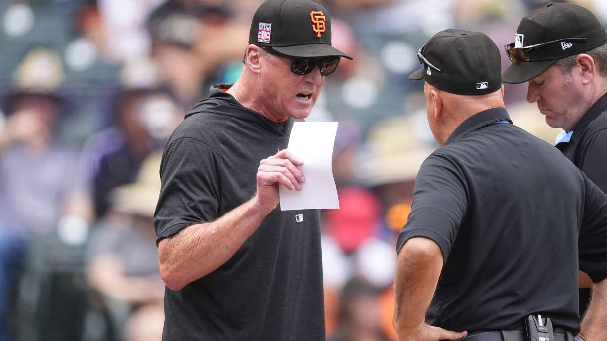 San Francisco Giants manager Bob Melvin, left, talks to umpires after turning in the lineup card before facing the Colorado Rockies in a baseball game Sunday, July 21, 2024, in Denver.
