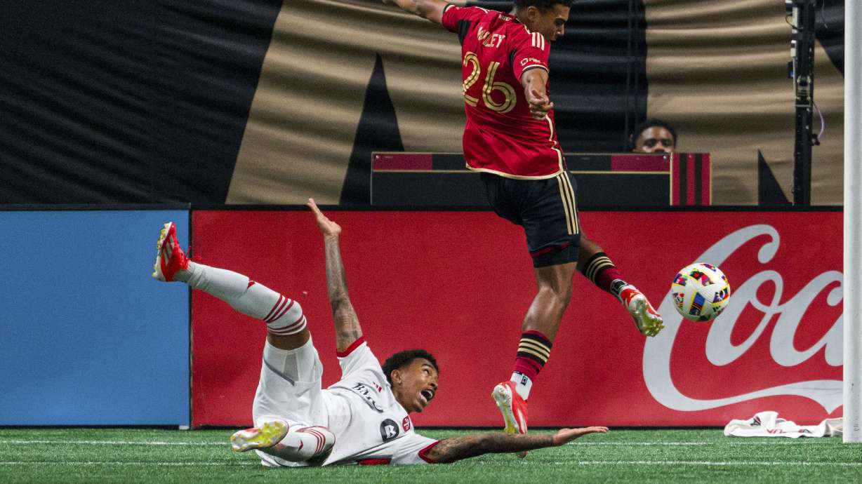 Toronto FC midfielder Jahkeele Marshall-Rutty, left, reacts as Atlanta United defender Caleb Wiley (26) kicks the ball during the first half of an MLS soccer match, Saturday, June 29, 2024, in Atlanta.