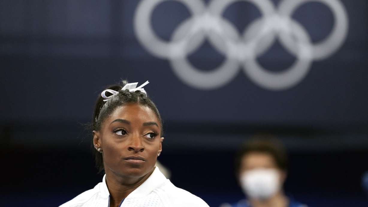 FILE - In this July 27, 2021 file photo, Simone Biles, of the United States, watches gymnasts perform after she exited the team final at the 2020 Summer Olympics, in Tokyo. Biles, who redefined excellence in gymnastics and picked up seven Olympic medals along the way, drew attention and, from some, criticism by pulling out of events in Tokyo because of a mental block that made her afraid to attempt certain dangerous moves.